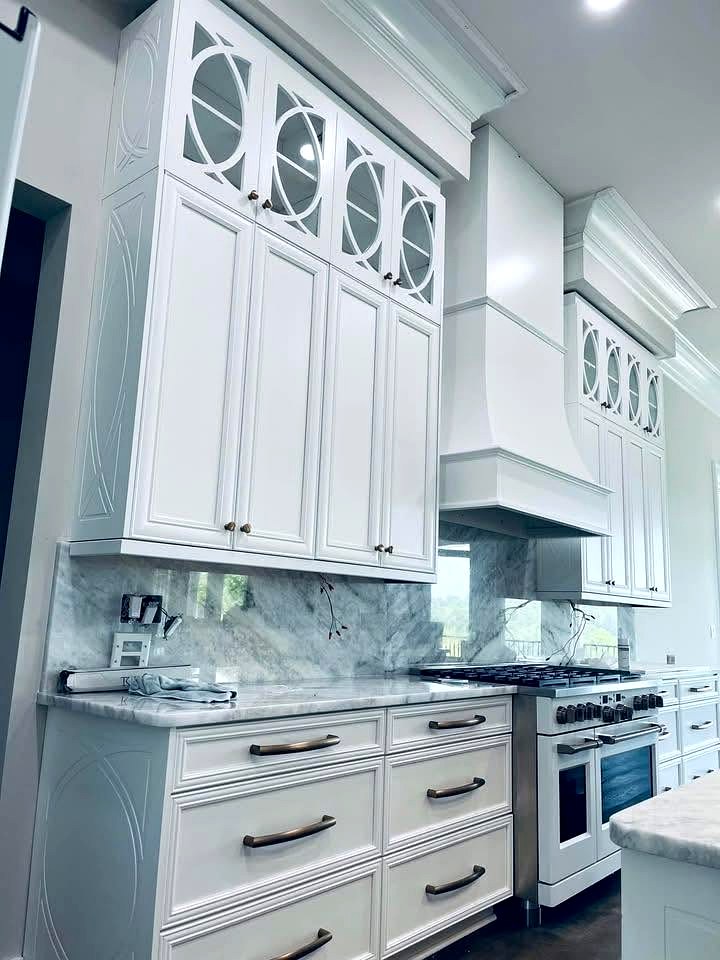 White mullion glass door cabinets with marble backsplash and painted range hood
