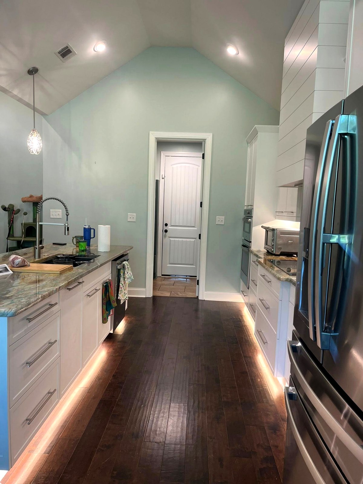White galley kitchen with under-cabinet lighting and granite counters