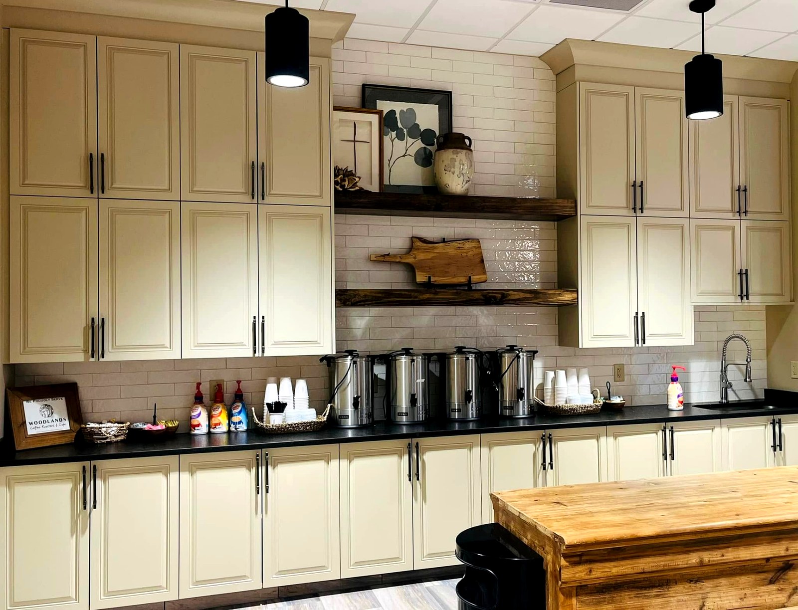 Commercial breakroom casework with cream cabinets and rustic floating shelves