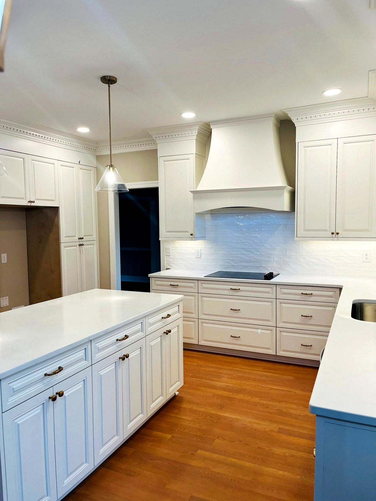 Cream raised panel kitchen with quartz island and painted range hood