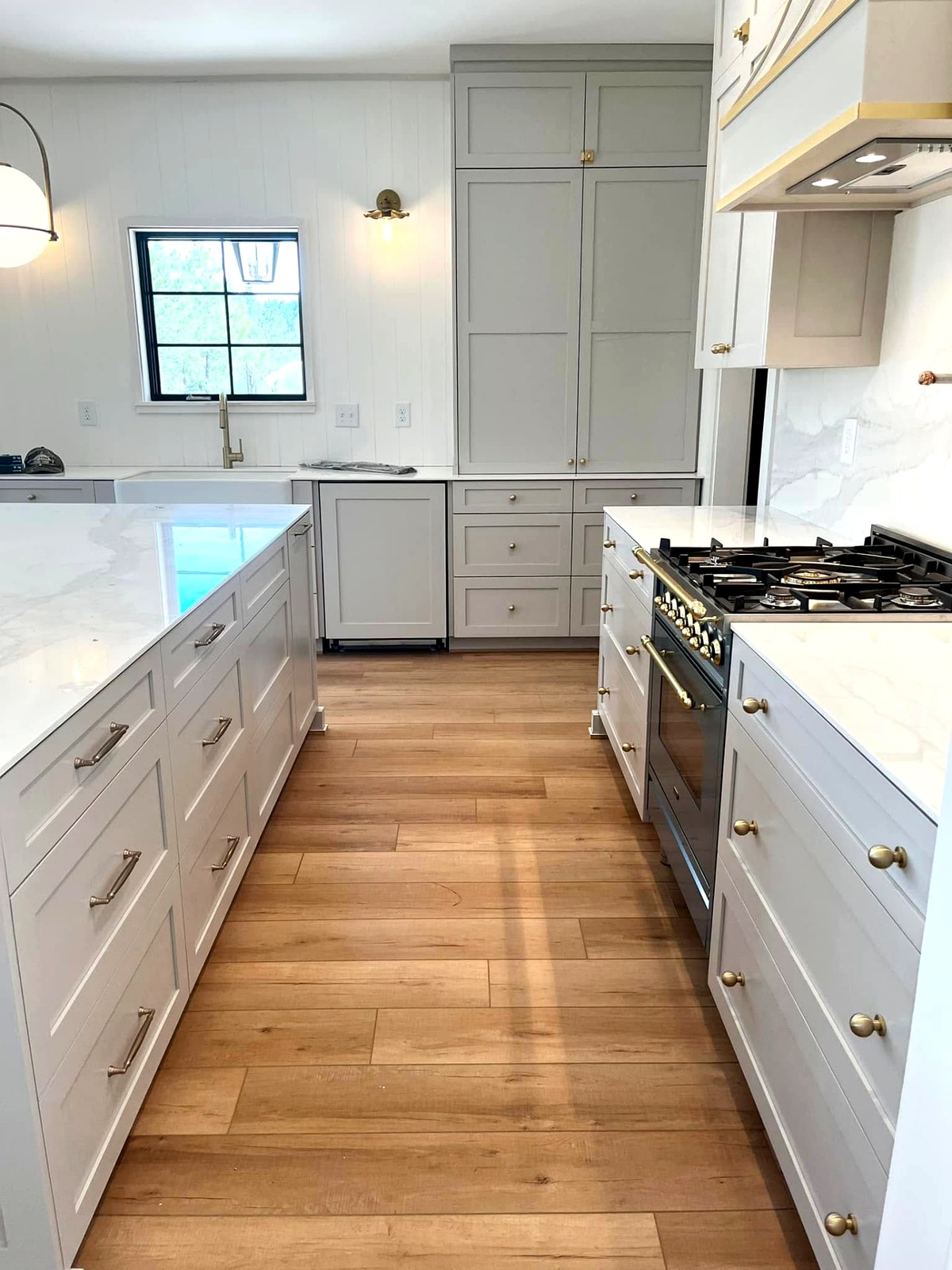 Greige inset shaker kitchen with marble counters and brass hardware